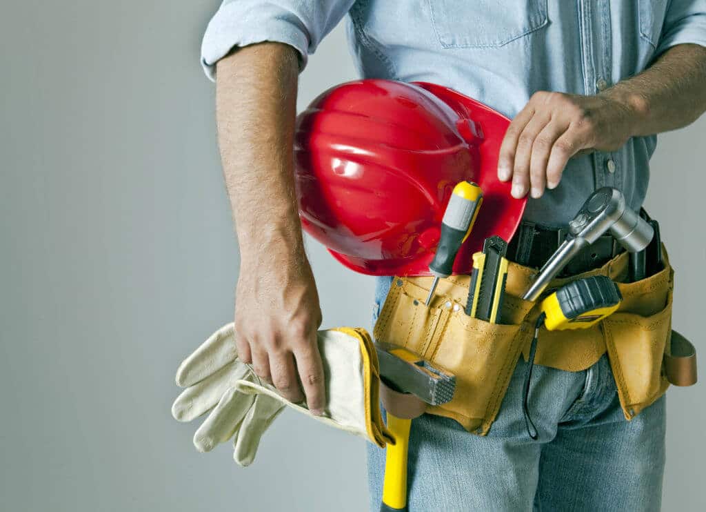 Handyman with a toolbelt that includes a hammer and a screwdriver, a red hard hat, and gloves